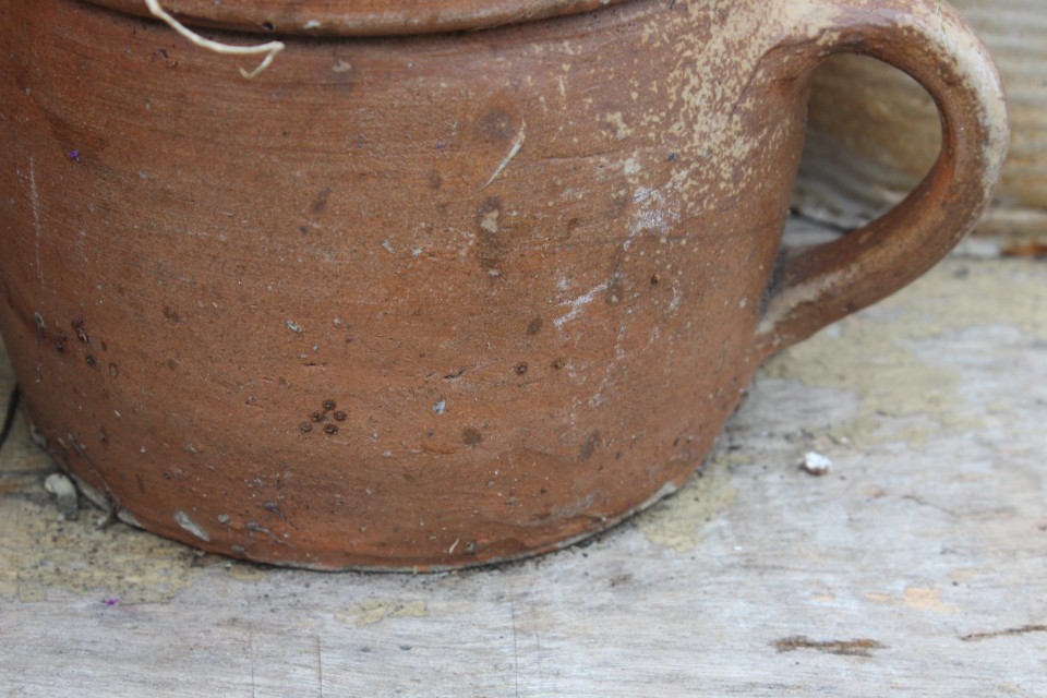 Oude ronde bruine aardewerk pot met oor